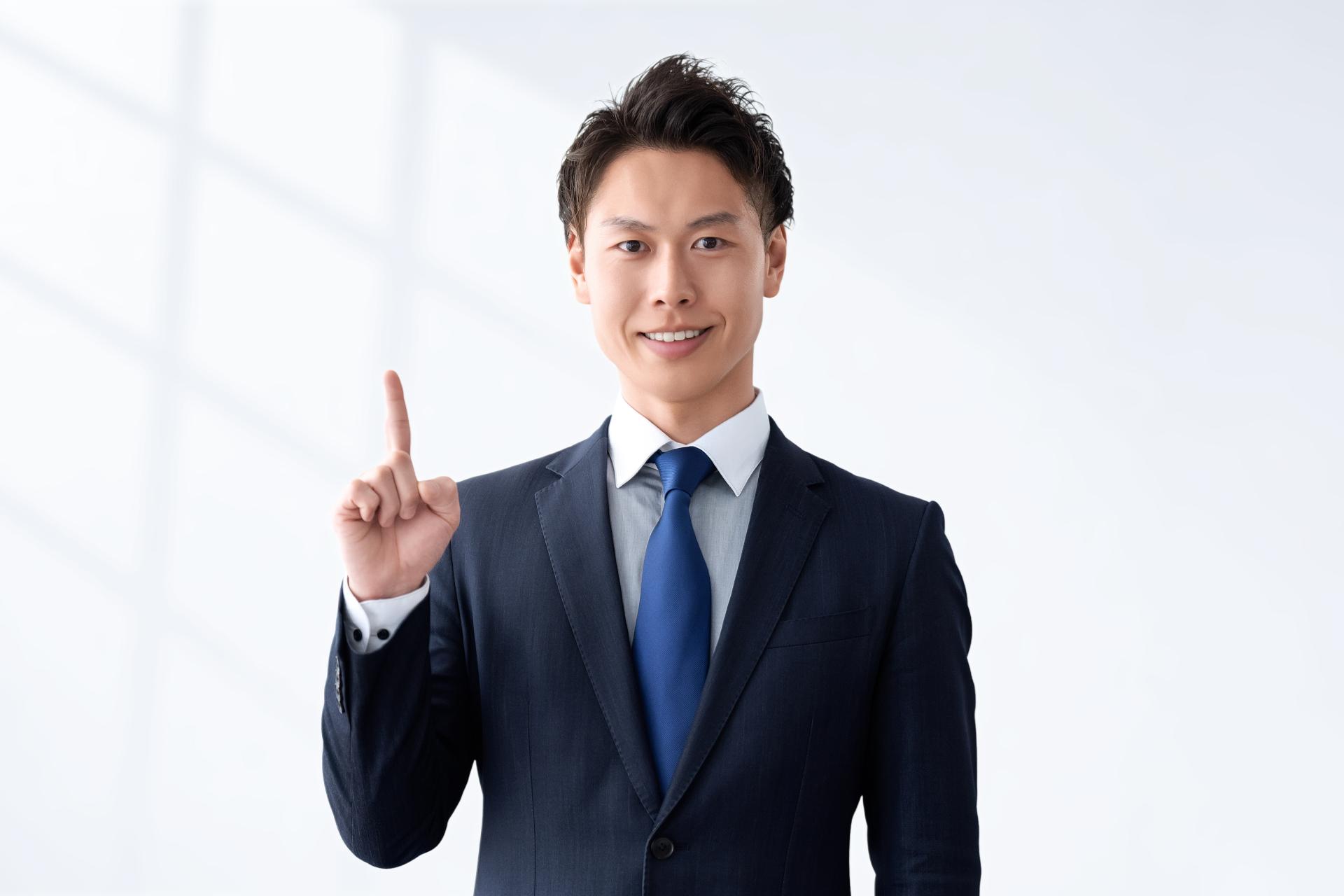 人差し指を立てるスーツの男性