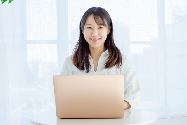 ノートPCの前で微笑む女性
