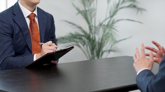 面接でメモを取るスーツの男性